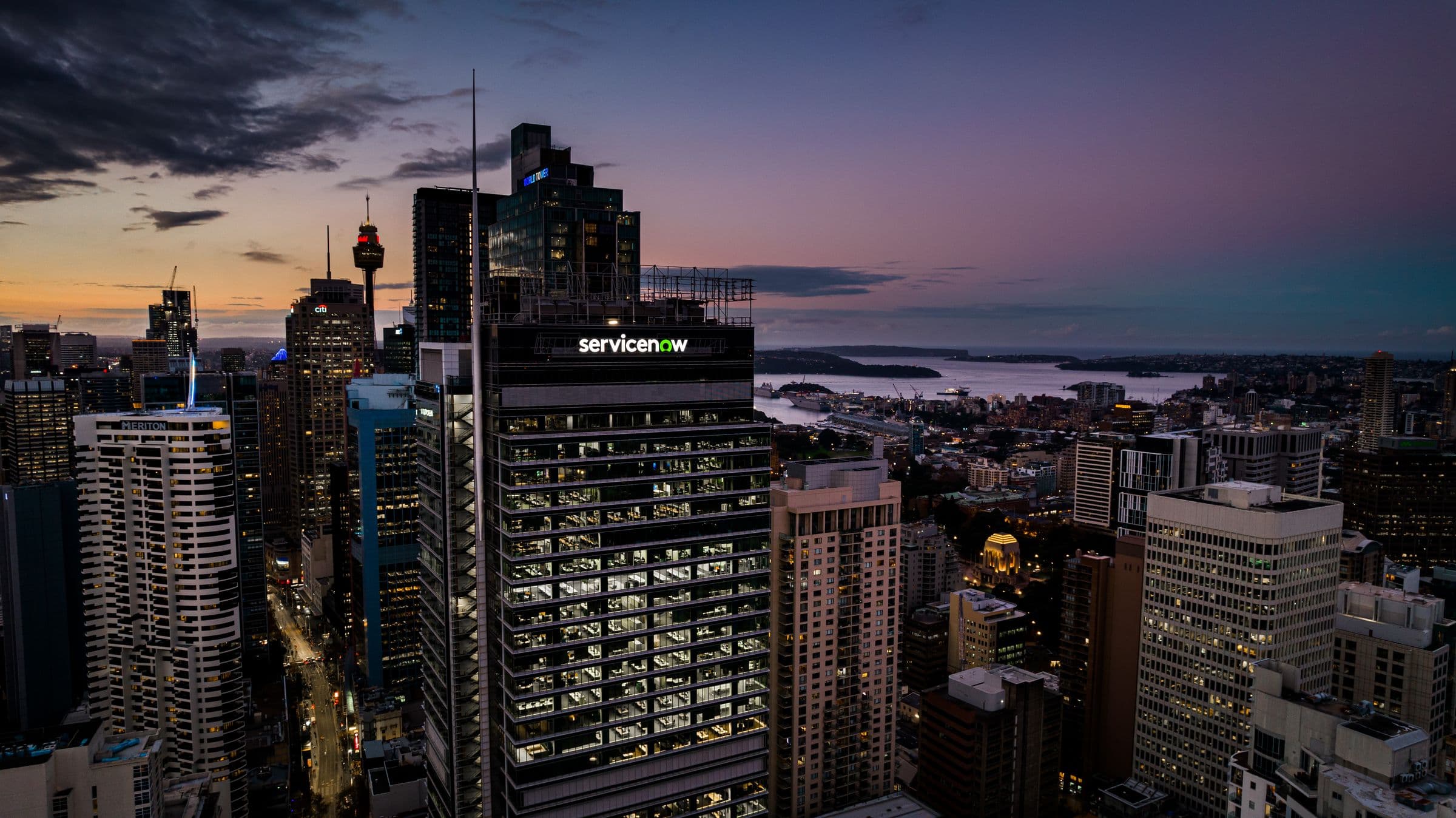 Sydney at dusk, the ServiceNow tower glowing over the CBD skyline